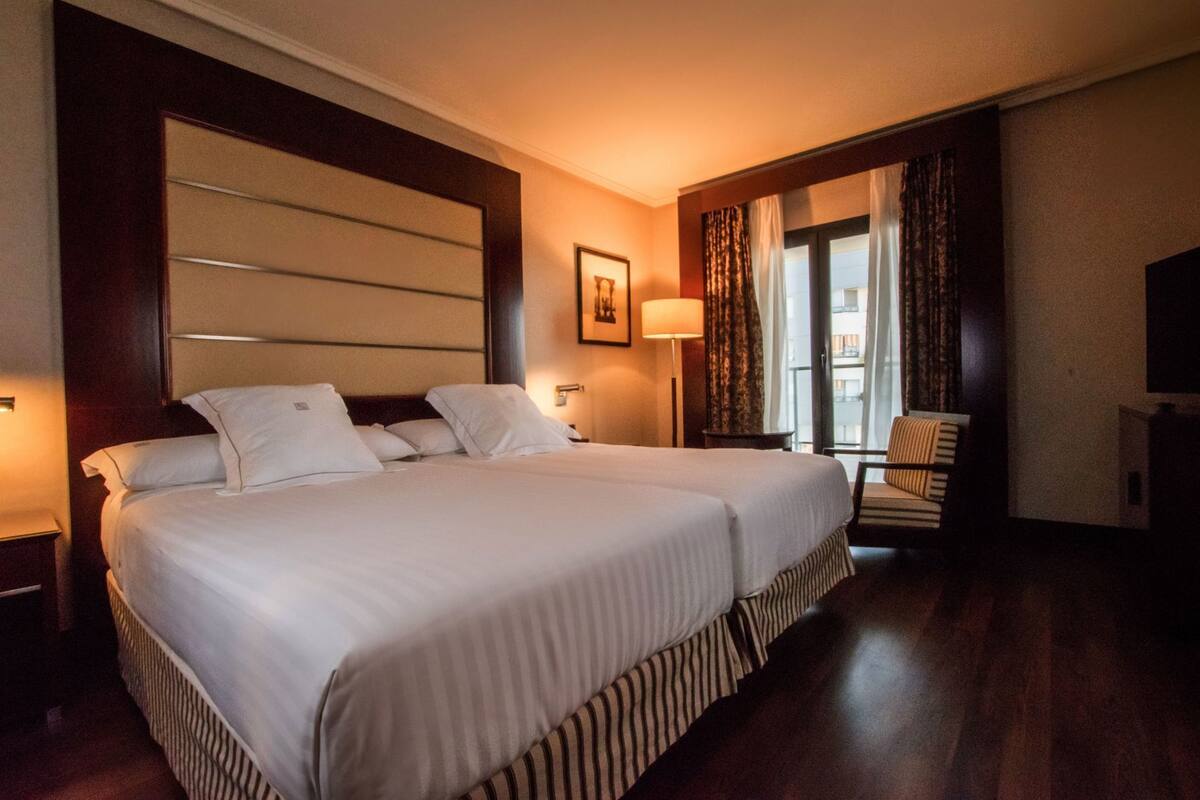 Una habitación de hotel con una cama grande, una silla, un escritorio y un televisor.