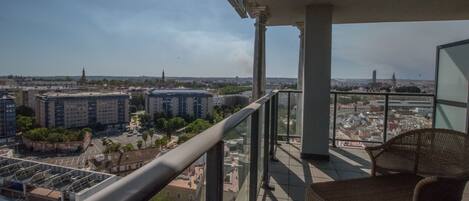 A balcony with a view of a cityscape, including buildings and a distant tower.