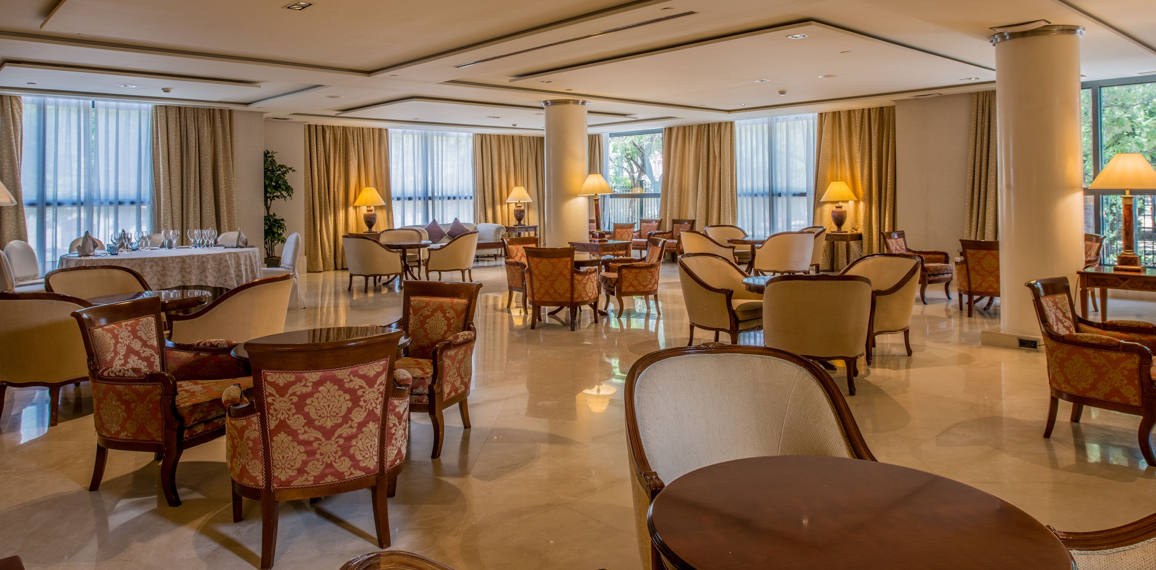 A spacious hotel lobby with multiple seating areas, large windows, and a polished floor.