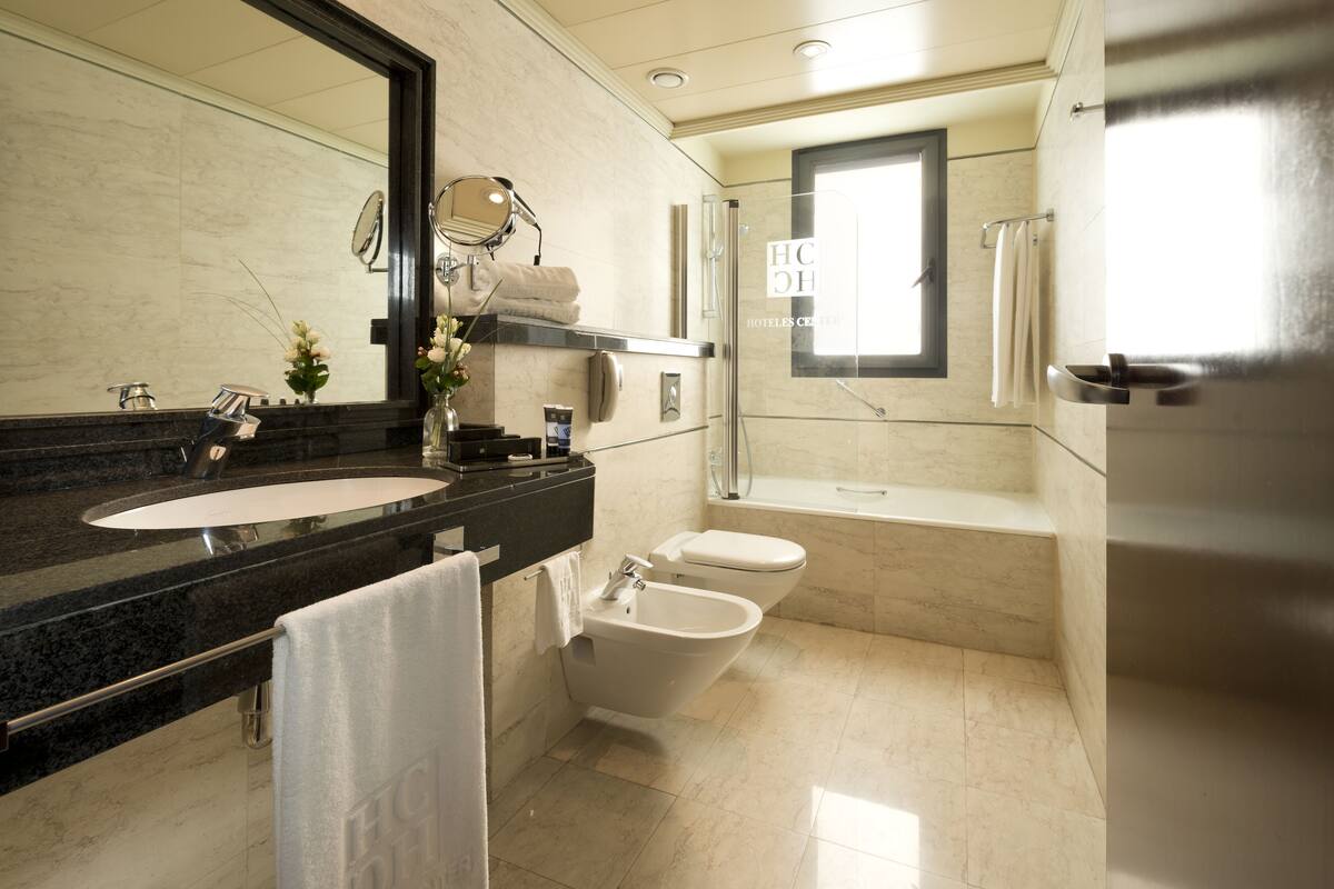 Un baño moderno con un espejo grande, un lavamanos, un bidé y una bañera.