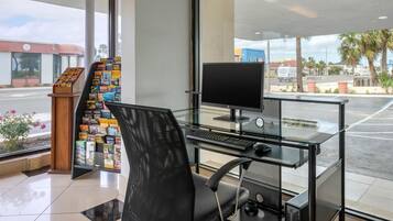 A reception area with a computer desk, a chair, a magazine rack, and a view of the street outside.