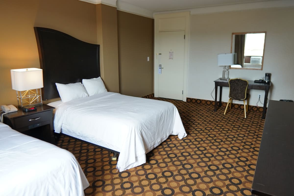 Una habitación de hotel con una cama grande, un escritorio, una silla y una lámpara de escritorio.