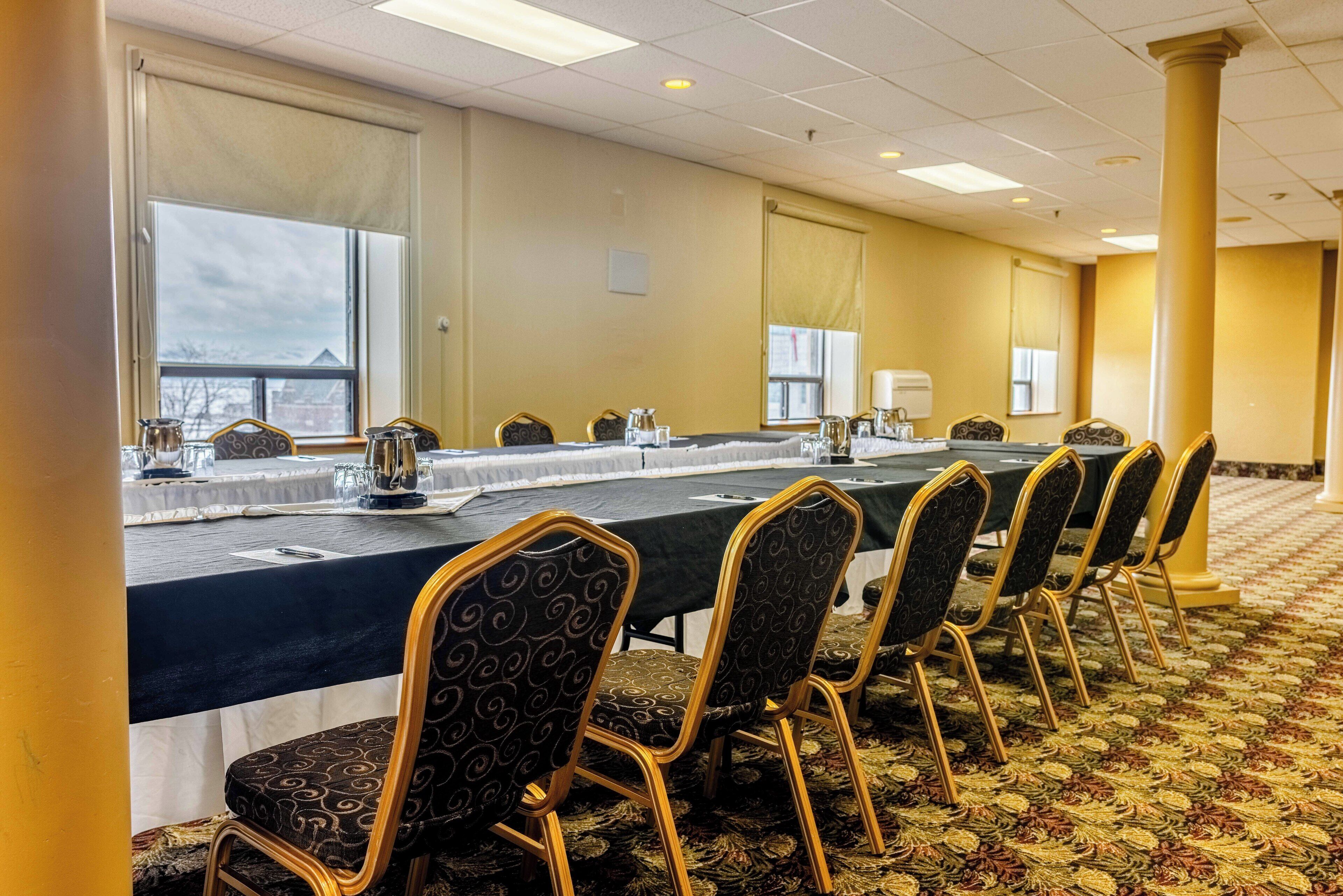 A conference room with a long table, chairs, and a carpeted floor.