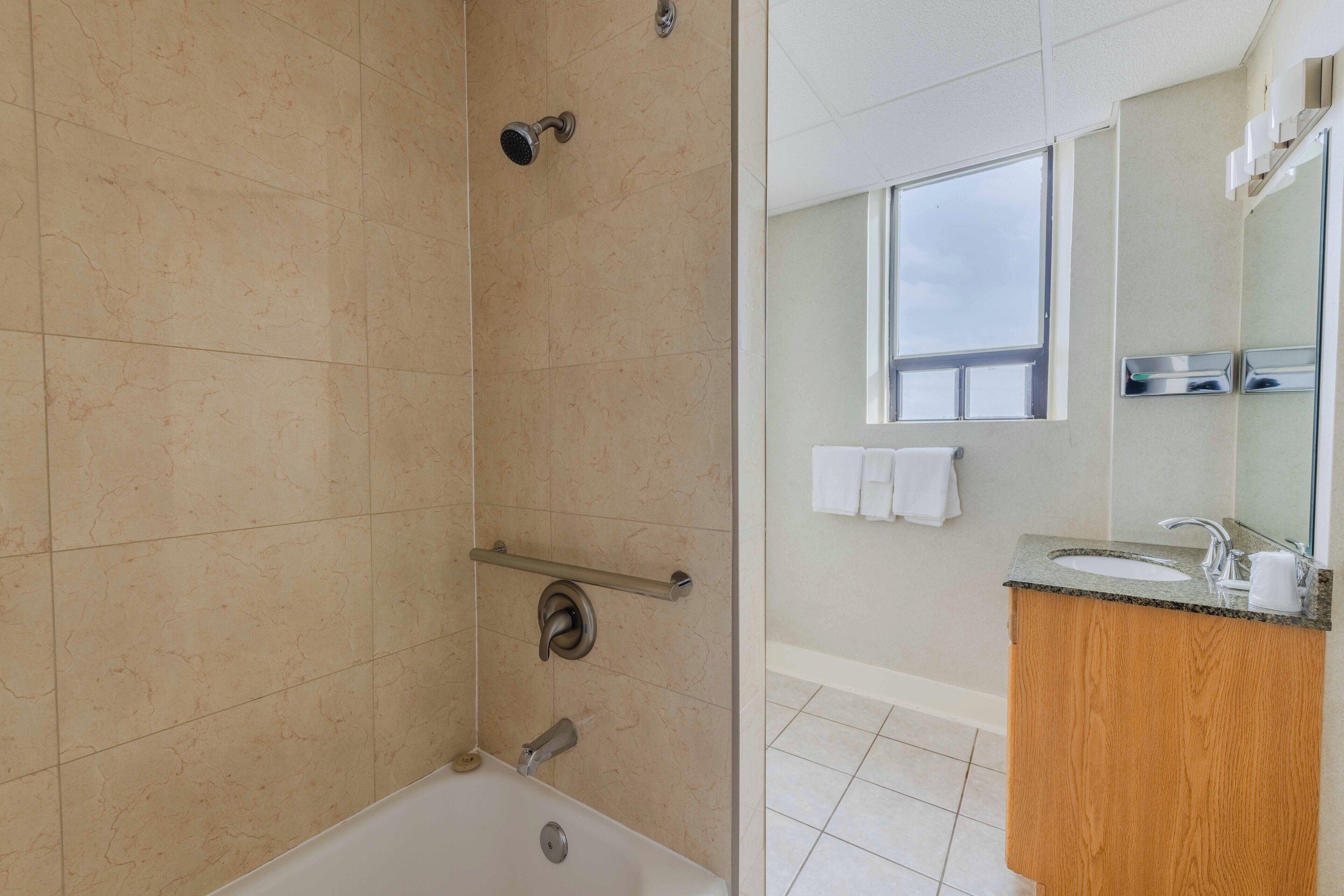 A bathroom with a shower, a sink, and a window.