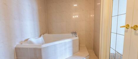 A modern bathroom with a freestanding bathtub, tiled walls, and a glass door leading to an outdoor area.