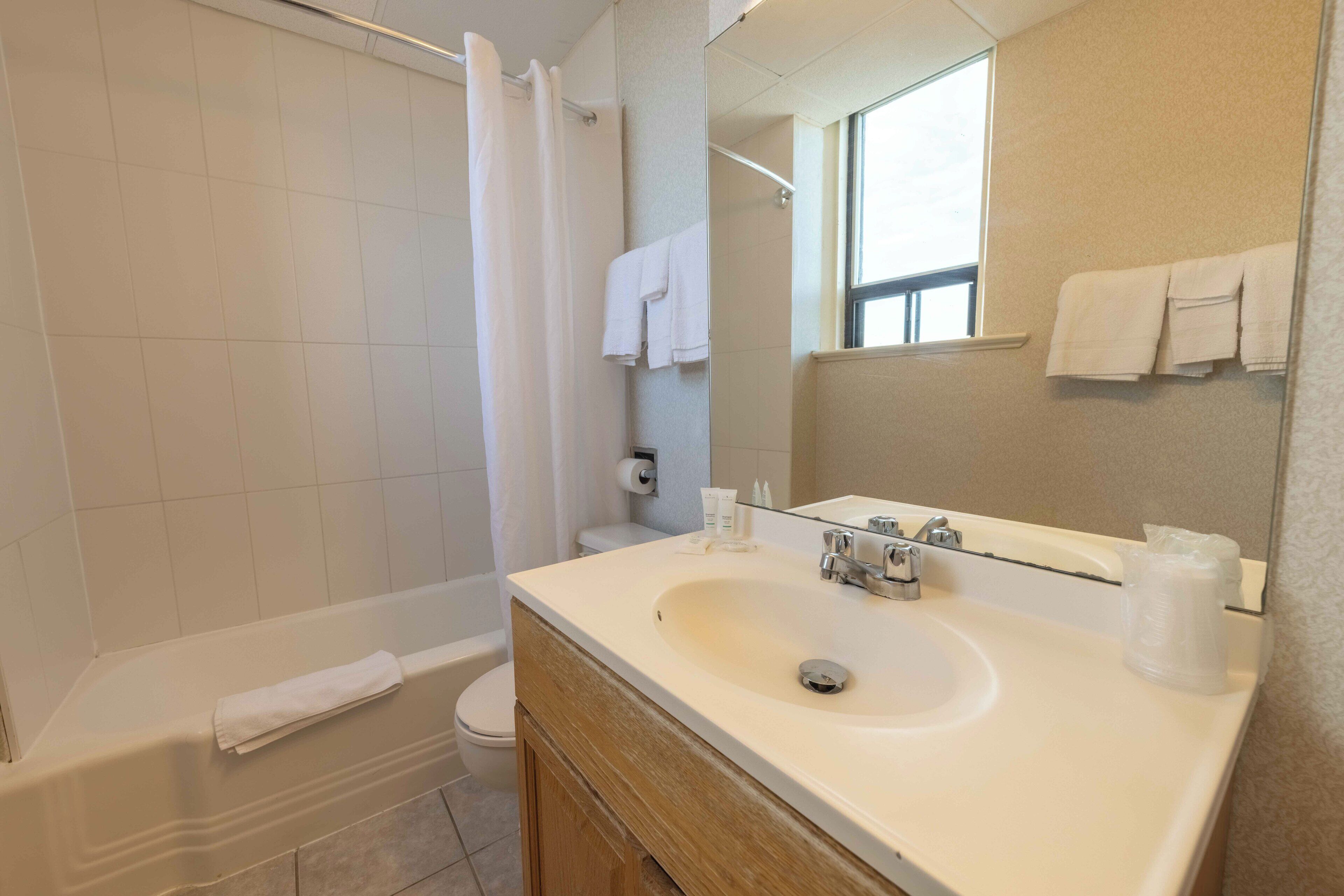 A bathroom with a bathtub, toilet, sink, and a large mirror.