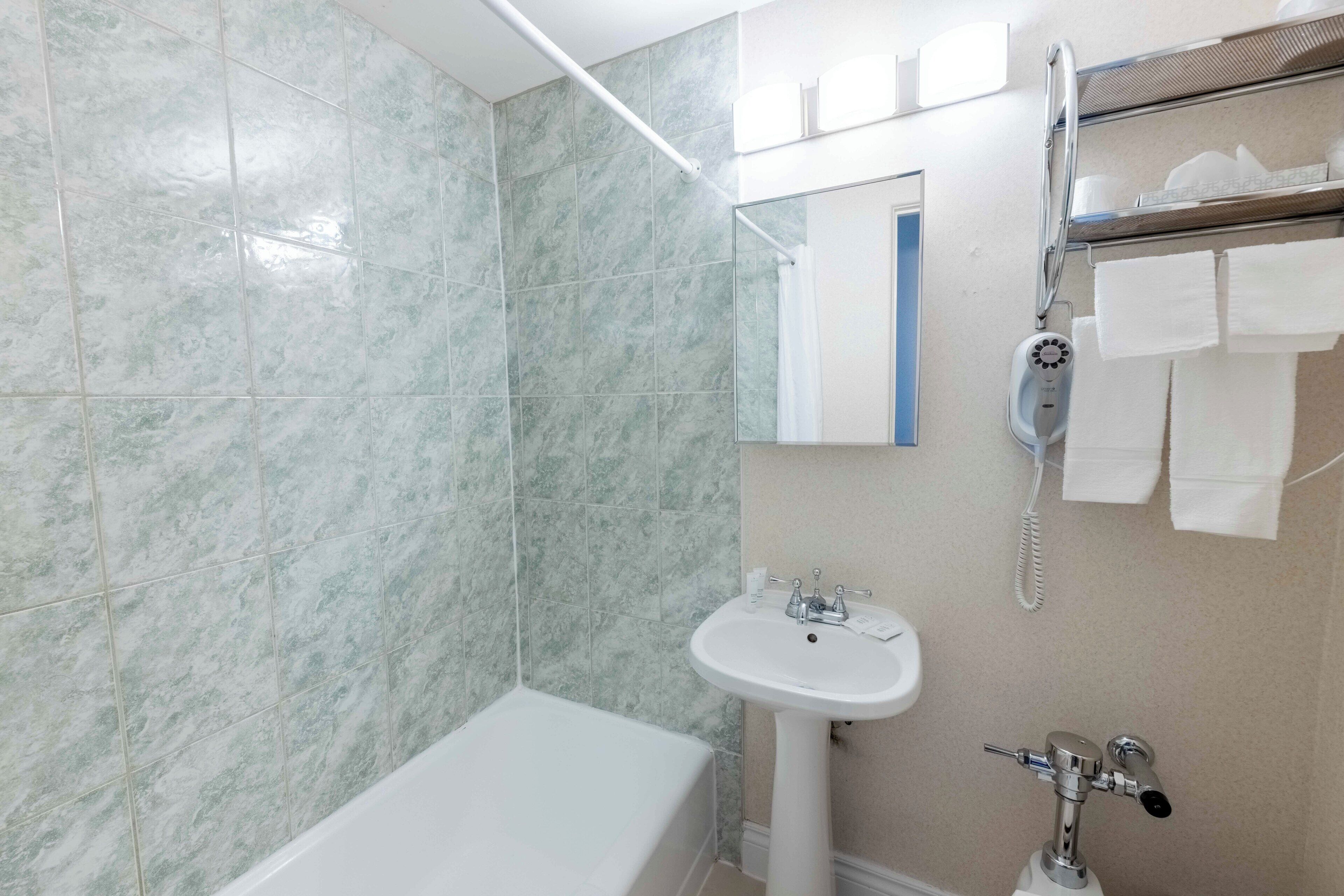 A bathroom with a bathtub, a sink, and a shower with a handheld showerhead.