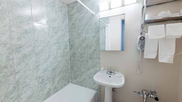 A bathroom with a bathtub, a sink, and a shower with a handheld showerhead.