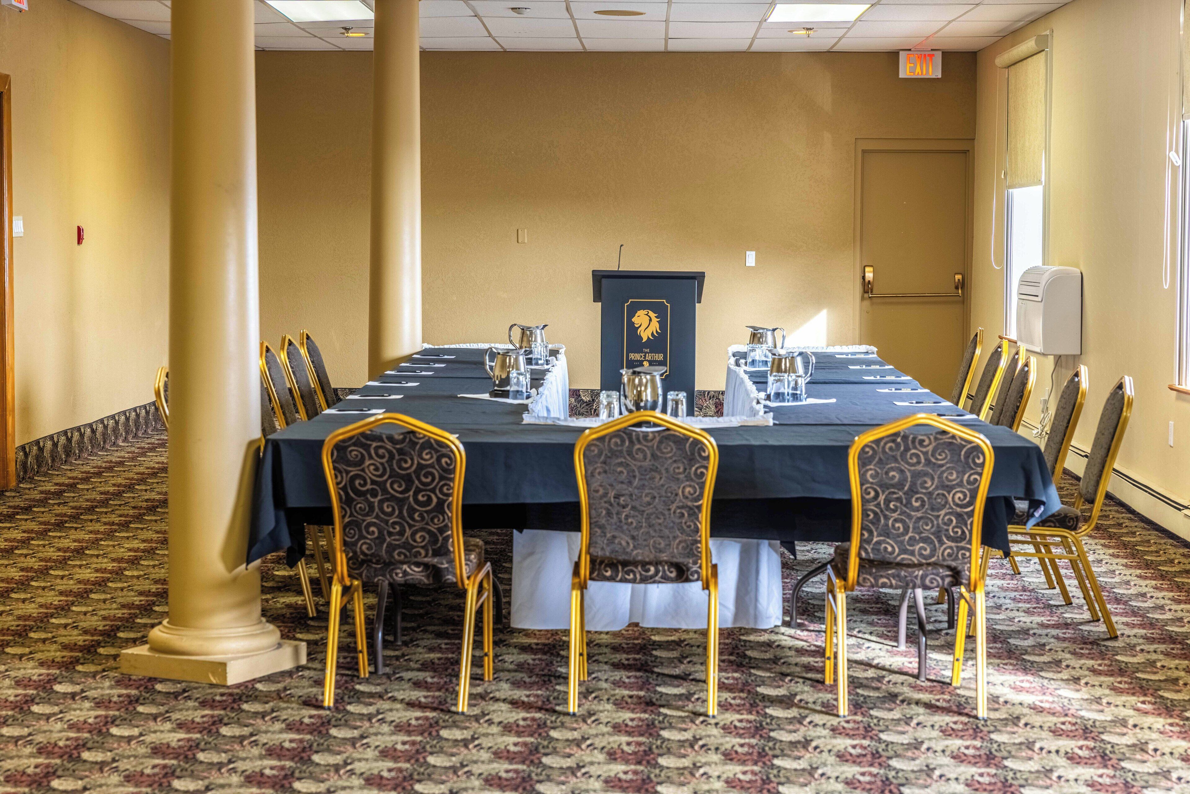 A conference room with a long table, chairs, and a podium.