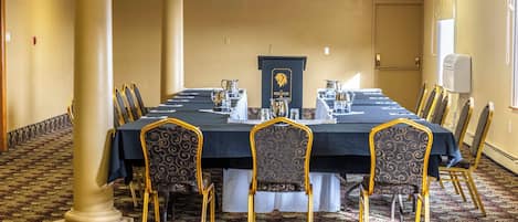 A conference room with a long table, chairs, and a podium.