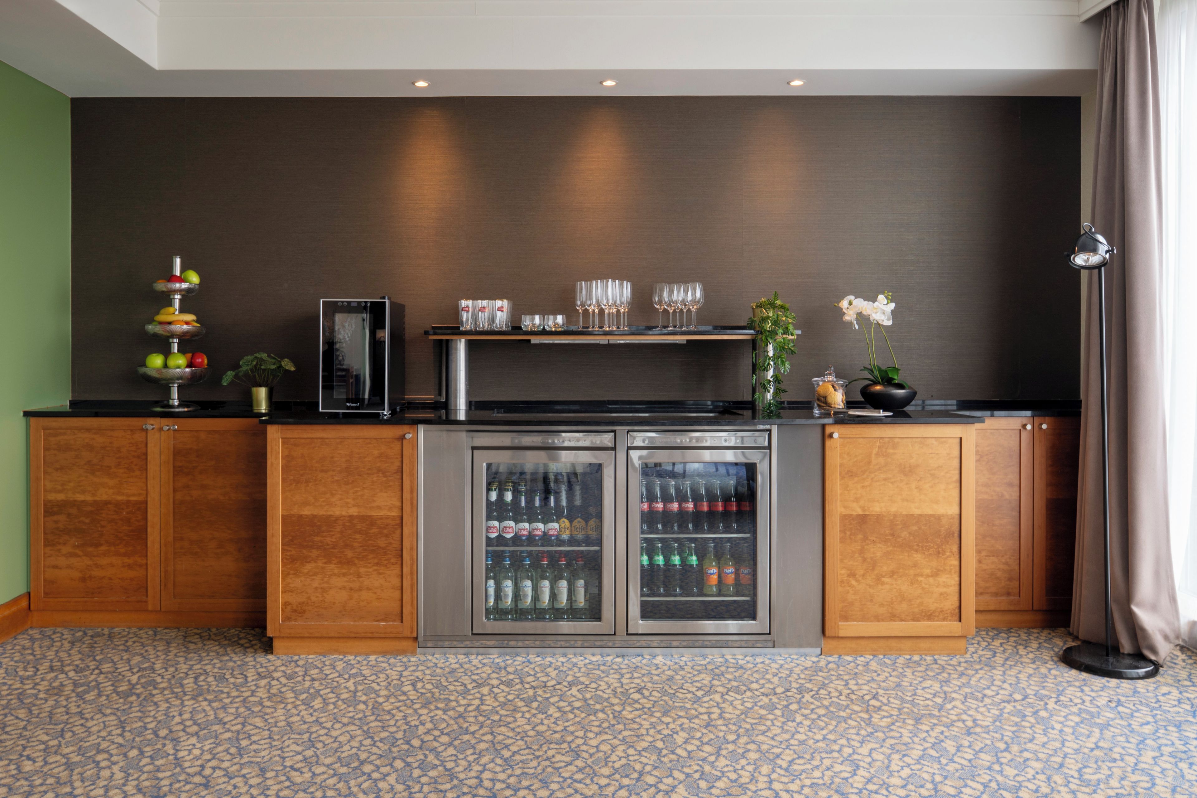 Zona de bar con minibar, una bandeja de frutas y una planta.
