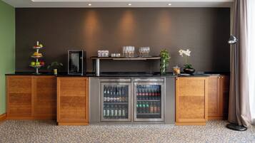 Zona de bar con minibar, una bandeja de frutas y una planta.