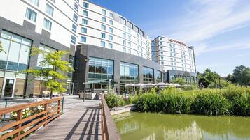 Un hotel moderno con fachada de vidrio, asientos al aire libre y una fuente de agua.