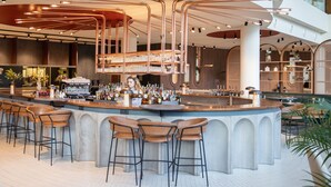 A modern bar area with a bar counter, stools, and a variety of bottles and glasses. - Crowne Plaza Brussels Airport by IHG (Machelen)