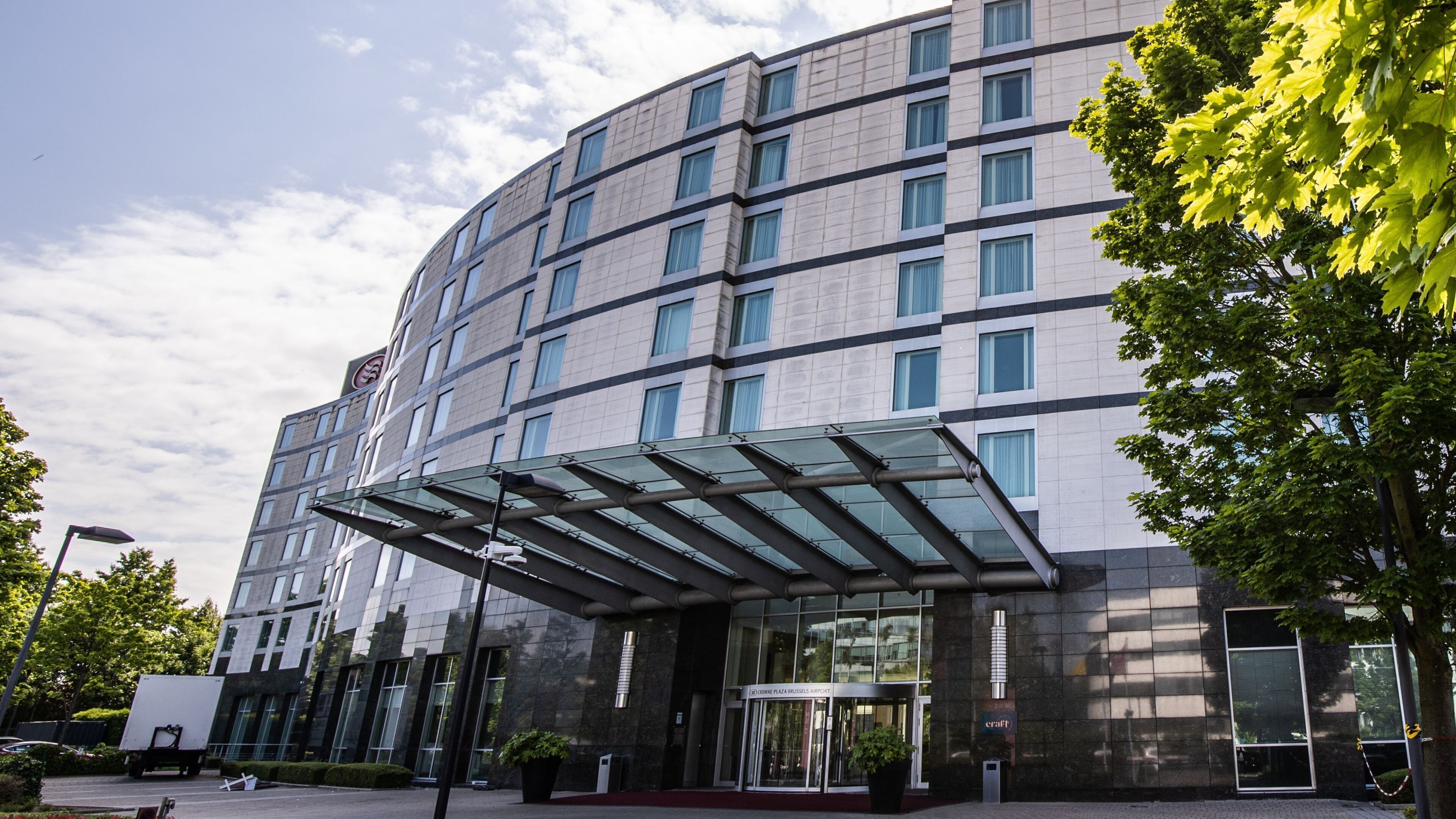 A modern building with a glass entrance, multiple floors, and a clear sky.