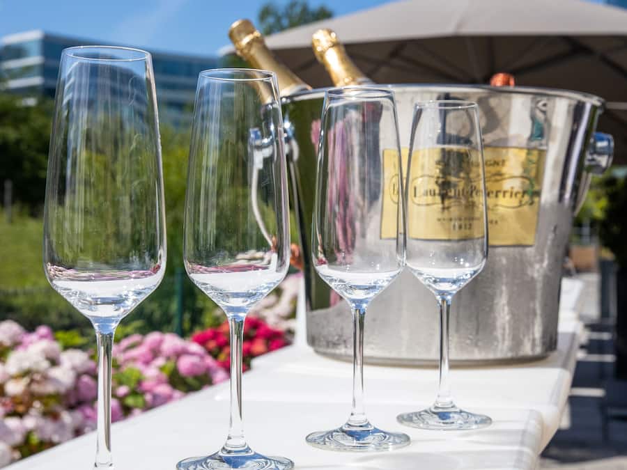 Four champagne flutes on a table with a champagne bucket in the background.