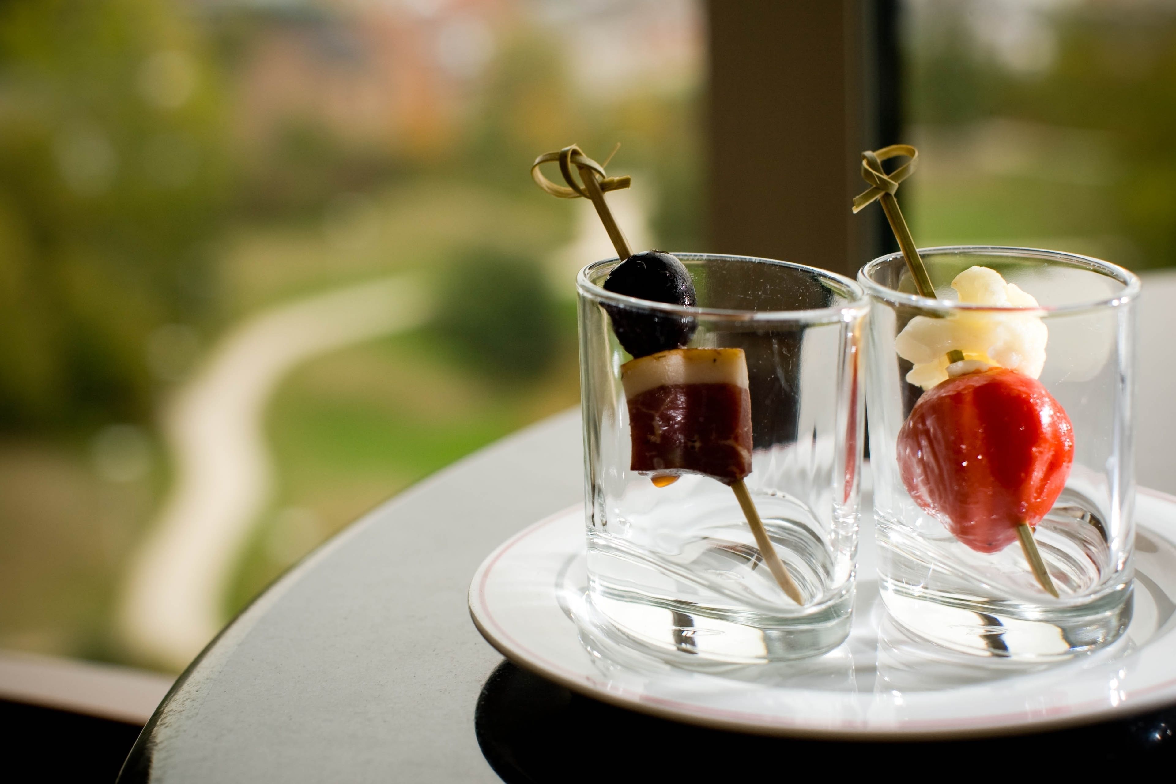 Two glasses of dessert with a clear view of a green landscape in the background.