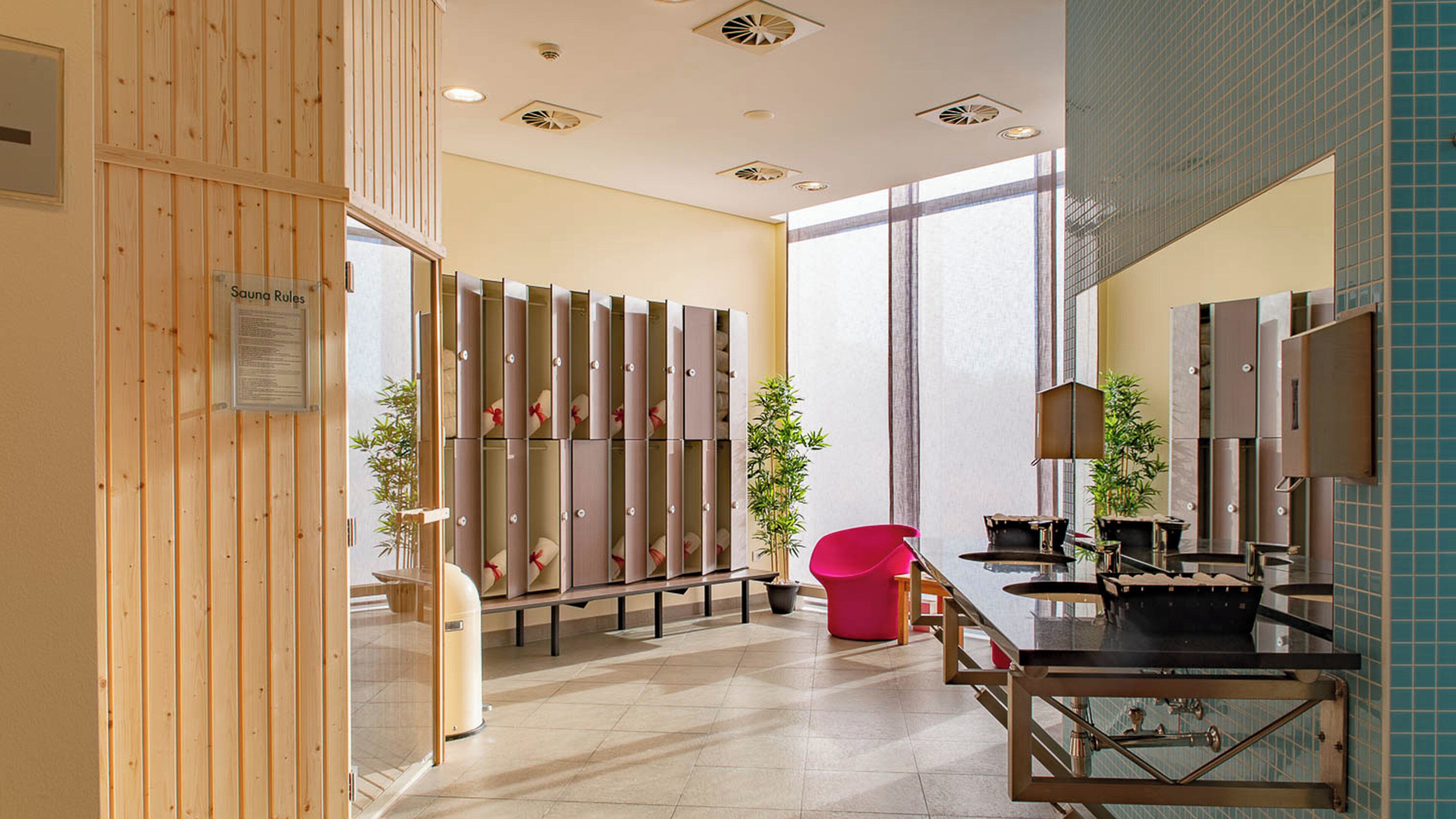 A modern bathroom with a sauna area, a red chair, and a sink with a mirror.