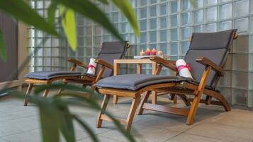 Een zithoek met houten stoelen en een tafeltje, tegen een glazen wand.