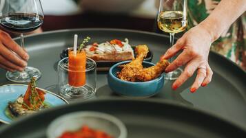 A dining table with various dishes, including a bowl of fried chicken, a glass of red wine, and a glass of white wine.