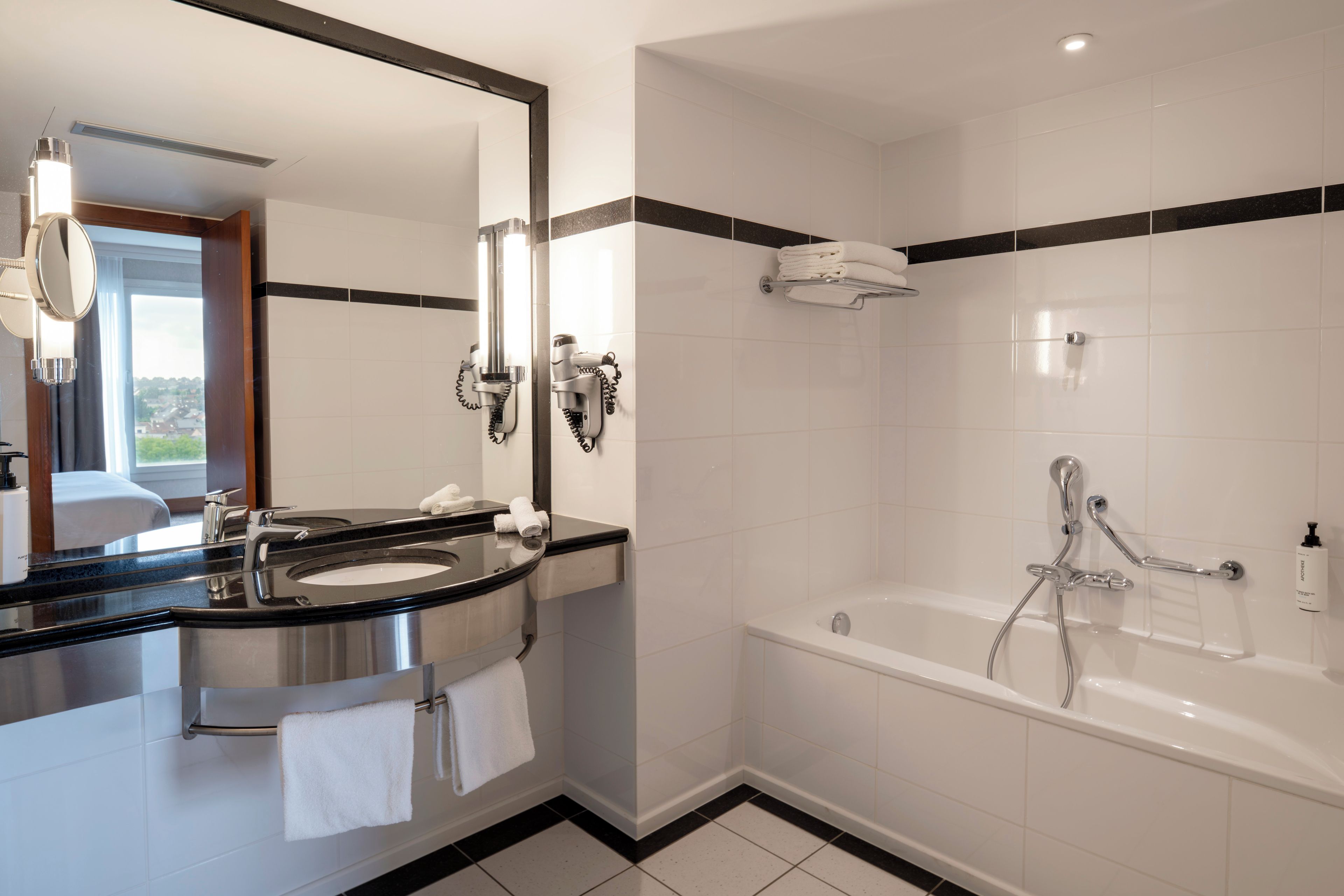 Een moderne badkamer met een wastafel, spiegel en een bad.