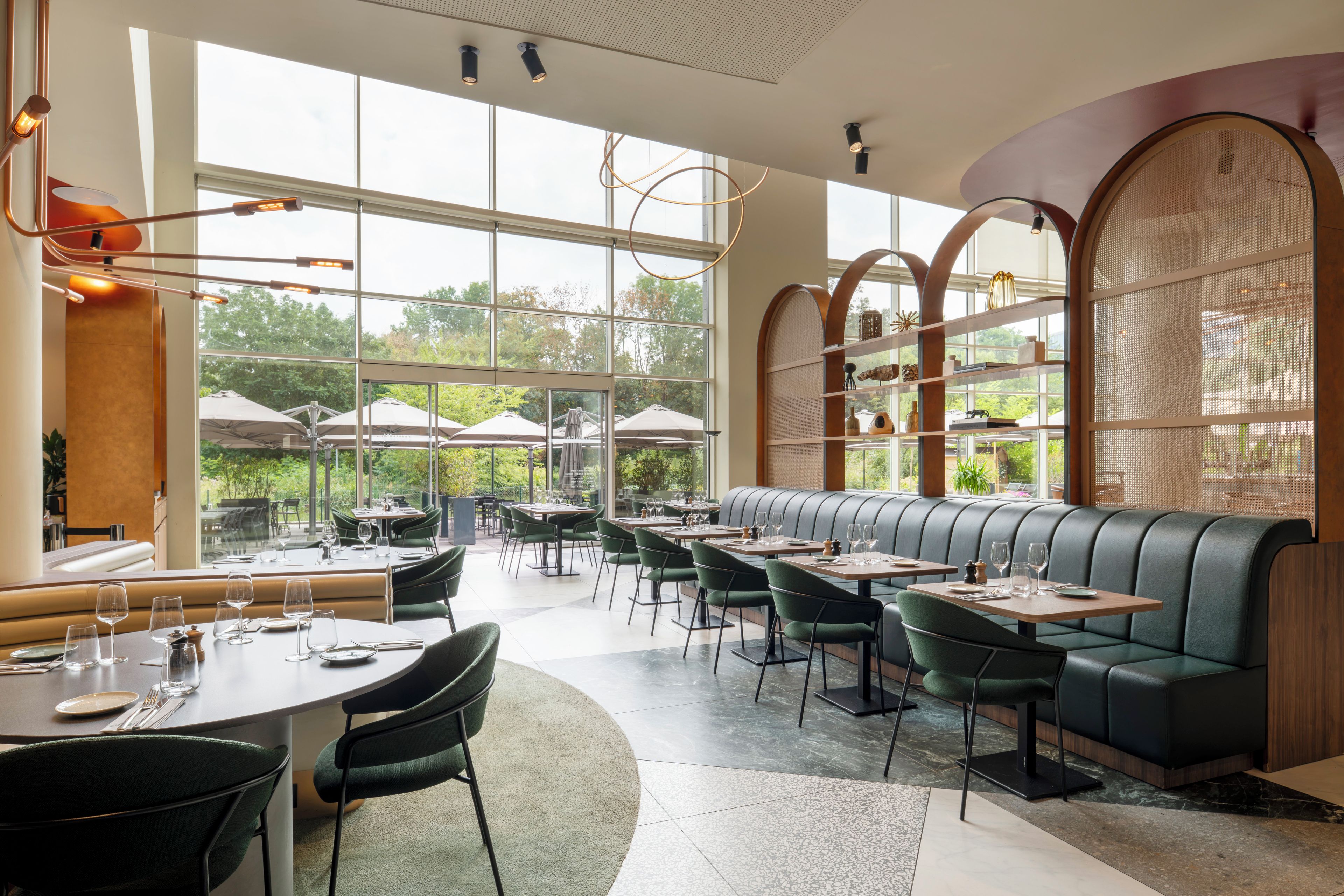Un restaurant au décor moderne, avec un espace de repos central doté d’un banc incurvé, entouré de tables et de chaises.