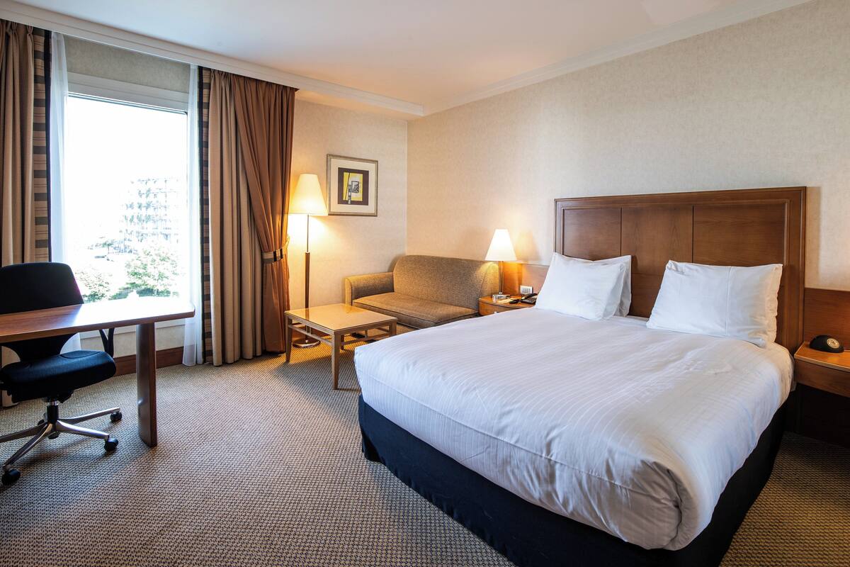 Une chambre d’hôtel avec un grand lit, un bureau, une chaise et deux lampes de chevet.