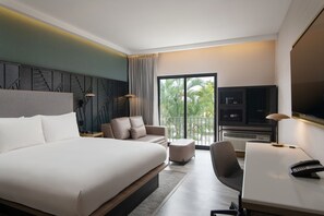 Une chambre d’hôtel moderne, dotée d’un grand lit, d’un bureau avec un téléphone, d’une chaise, d’un canapé et d’une télévision.