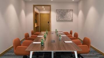 A conference room with a long table, orange chairs, and a wooden floor.