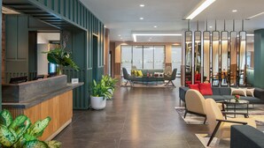 Eine moderne Hotelhalle mit Rezeption, Sitzgelegenheiten und großen Fenstern.