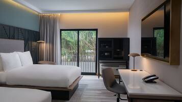 A hotel room with a large bed, a desk with a chair, a telephone, and a television.