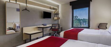 A hotel room with two beds, a desk, a chair, a TV, and a large window with a view.