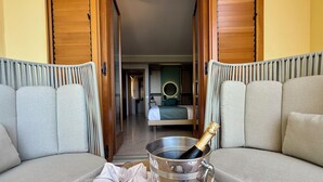 A room with a bed, a bedside table with a bottle of champagne, and a sofa. - Hotel Panoramic (San Vito Lo Capo)