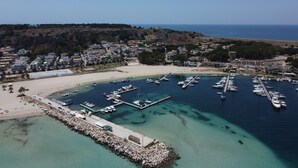 An aerial view of a coastal town with a marina, sandy beach, and residential buildings. - Hotel Panoramic (San Vito Lo Capo)