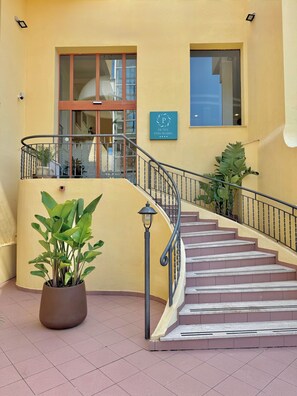 A hotel entrance with a staircase, a potted plant, and a sign indicating the hotel name. - Hotel Panoramic (San Vito Lo Capo)