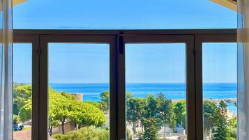 Ein Zimmer mit einem großen Bogenfenster und Blick auf die Küste mit Bäumen und Gebäuden.