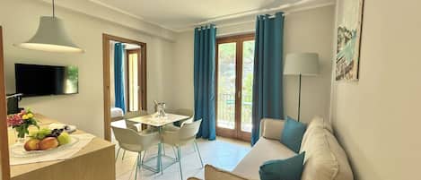 A modern hotel room with a dining area, a sofa, and a TV.