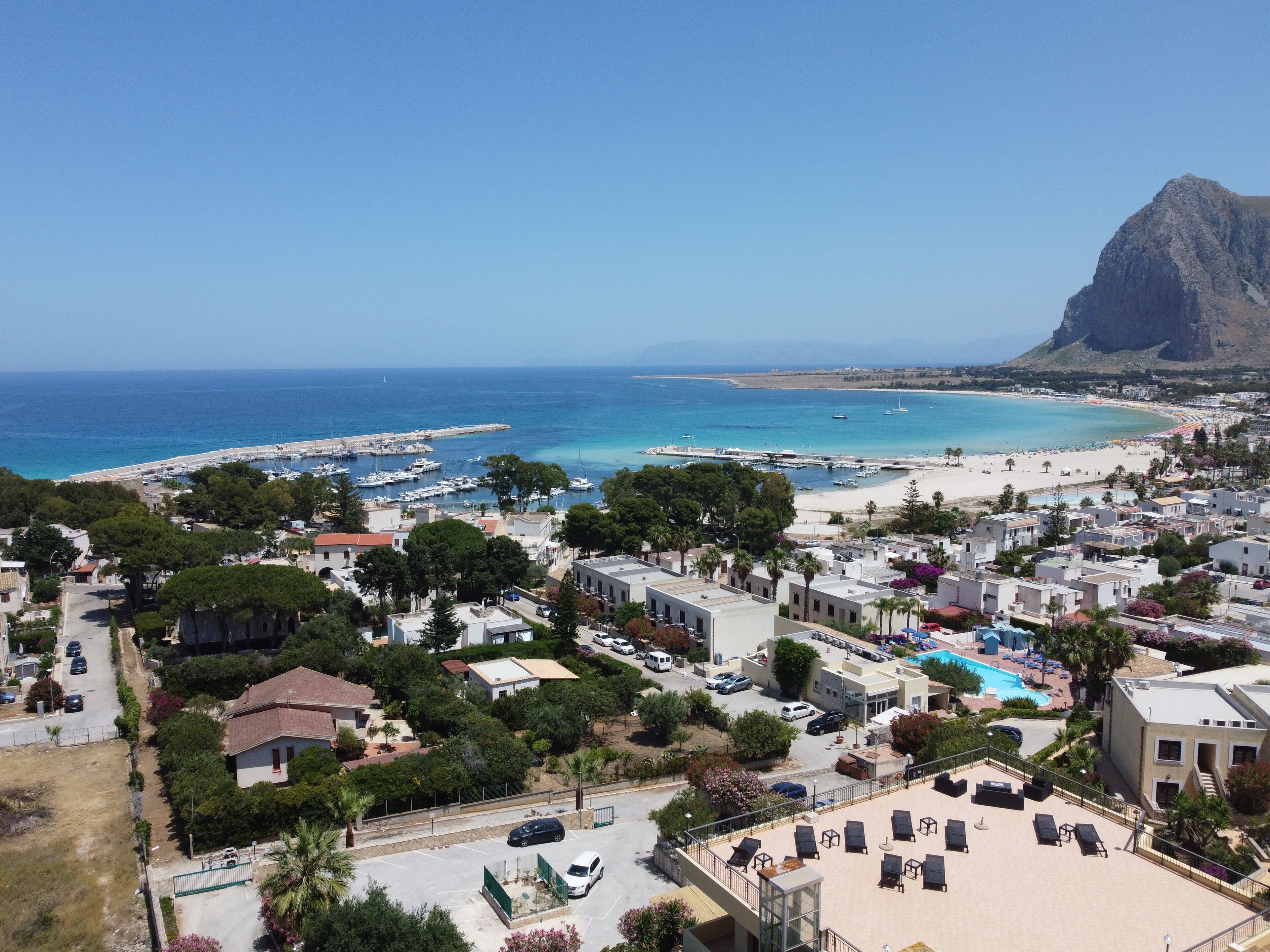 Un pueblo costero con un puerto deportivo, playa y edificios residenciales.