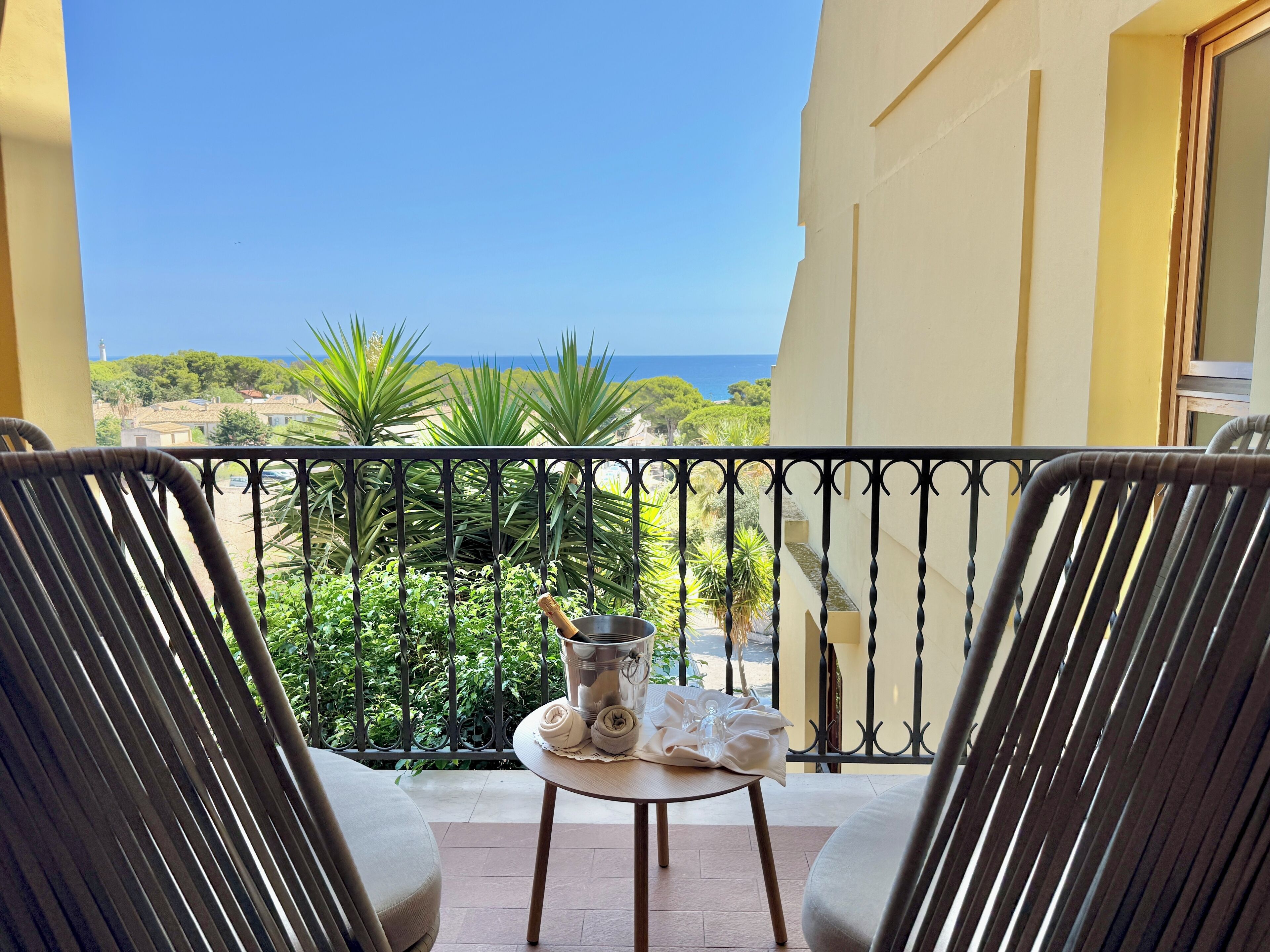 Un balcon avec deux chaises, une petite table et une vue sur la mer.
