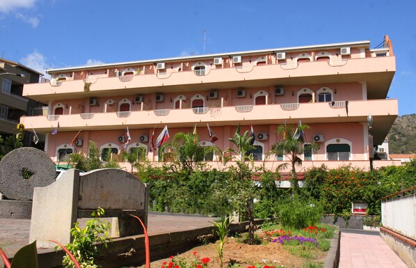 A multi-story building with balconies and flags.