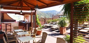 A covered outdoor area with wooden furniture, a bar, and potted plants. - Hotel D'Orange D'Alcantara (Francavilla di Sicilia)