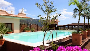 A swimming pool with a wooden deck, surrounded by potted plants and flowers. - Hotel D'Orange D'Alcantara (Francavilla di Sicilia)