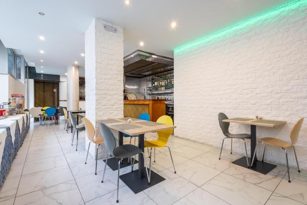 Un ristorante moderno con pareti in mattoni bianchi, una zona bar e diversi tavoli con sedie.