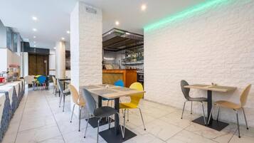 Un ristorante moderno con pareti in mattoni bianchi, una zona bar e diversi tavoli con sedie.