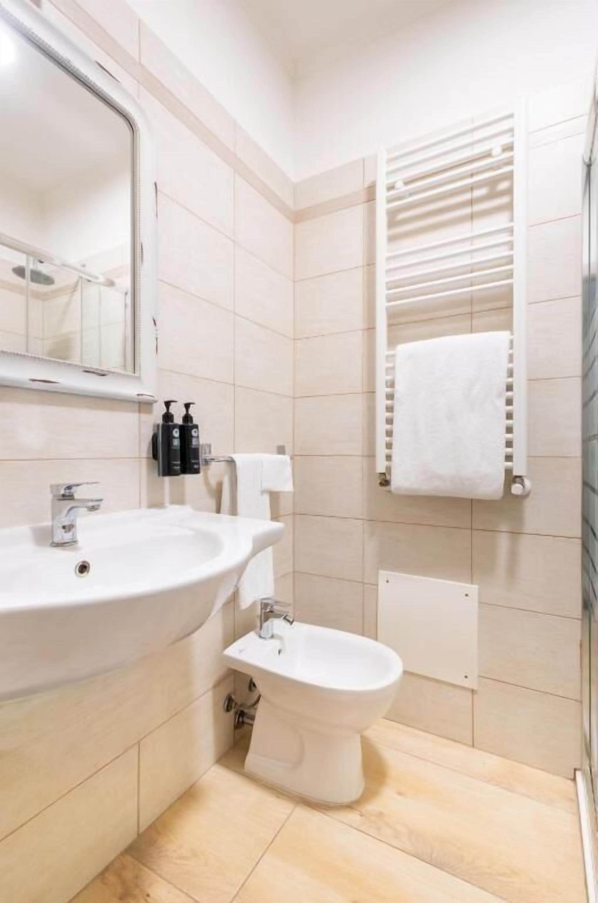 Un bany modern amb un lavabo, mirall, vàter i paraigua de tovalloles.