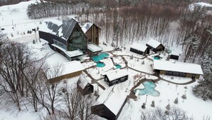 A modern lodge with multiple swimming pools, surrounded by snow-covered grounds and trees.
