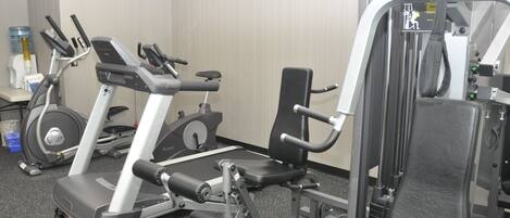 A gym with cardio machines, weightlifting equipment, and a water dispenser.