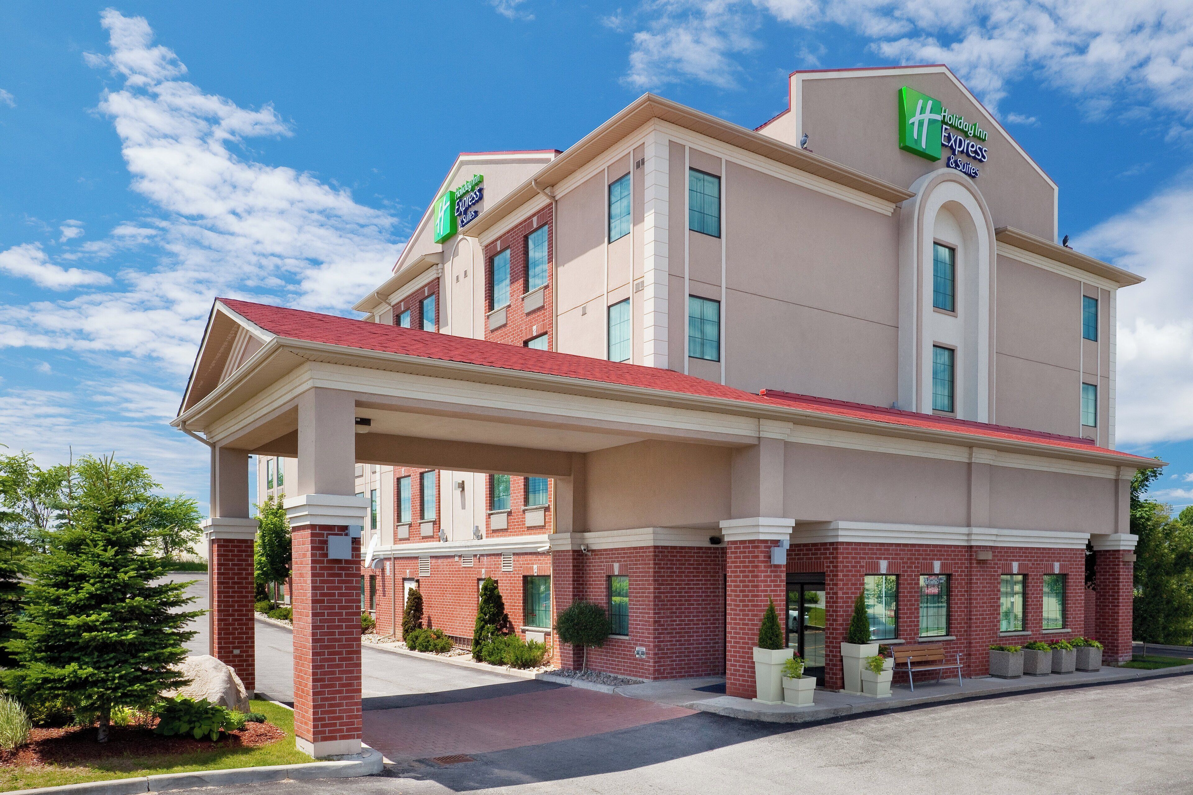 A Holiday Inn Express & Suites hotel with a brick facade, large windows, and a covered entrance.