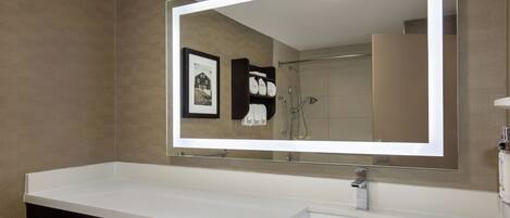 A bathroom with a large mirror, a white sink, and a towel rack.