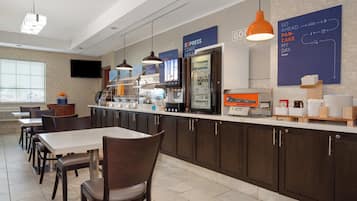 A breakfast area with a counter, seating, and a television.